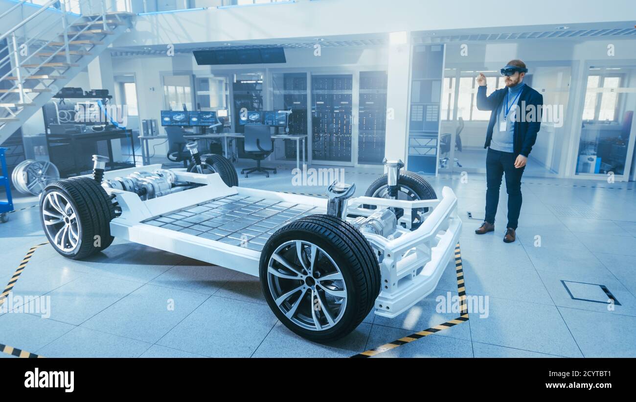 Ingénieur automobile travaillant sur la plate-forme de châssis de voiture électrique, à l'aide d'un casque de réalité augmentée. Dans le concept d'installation de laboratoire d'innovation cadre de véhicule Banque D'Images