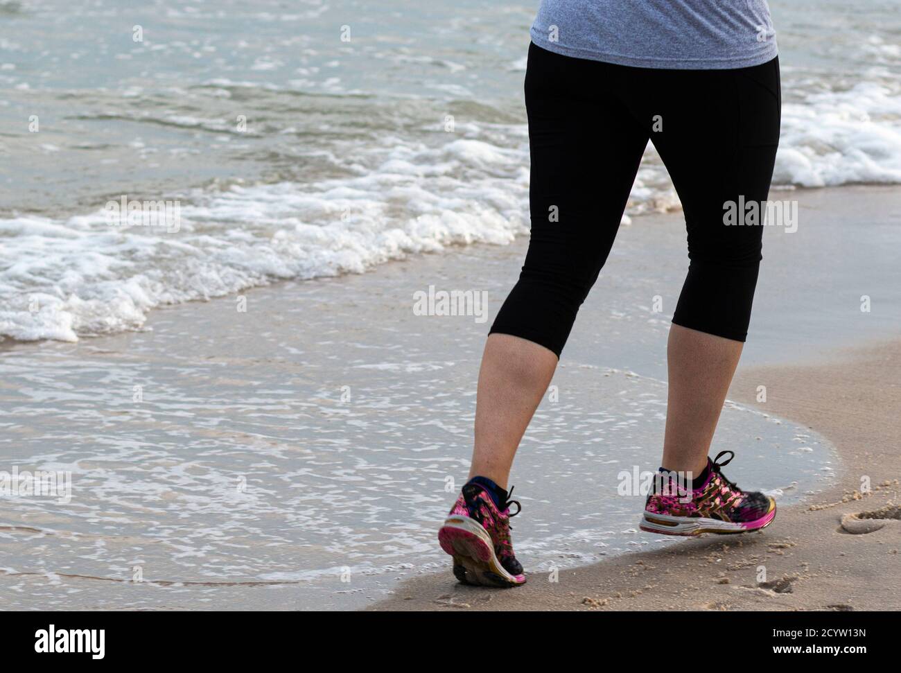 Vue arrière d'un coureur court sur le sable dur près de l'océan en spandex. Banque D'Images