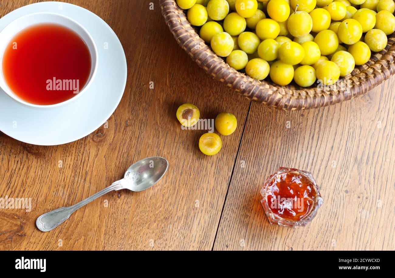 Une tasse de thé noir, prunes mirabelle jaunes et confiture de prunes sur une table en bois, vue du dessus Banque D'Images