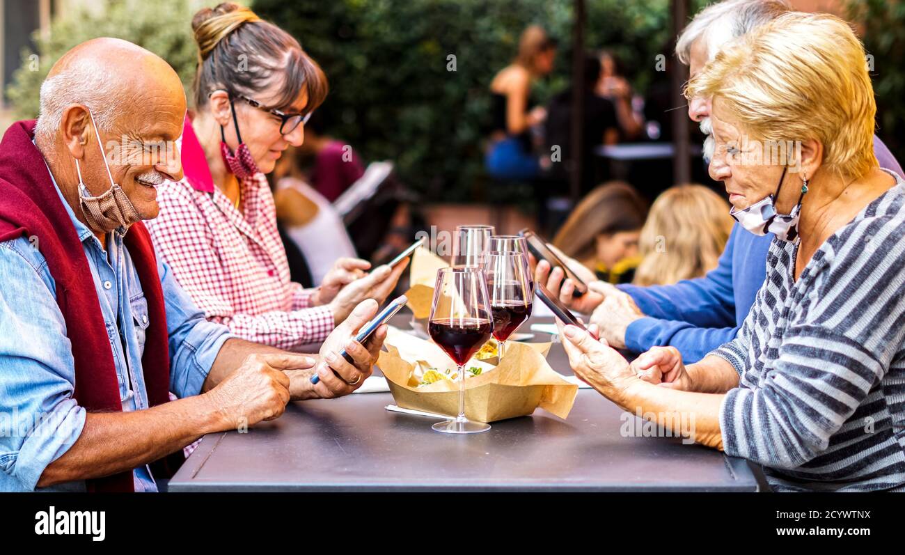 Les personnes âgées utilisant un smartphone à l'extérieur - les personnes âgées buvant du vin et S'amuser au restaurant - couples âgés Banque D'Images