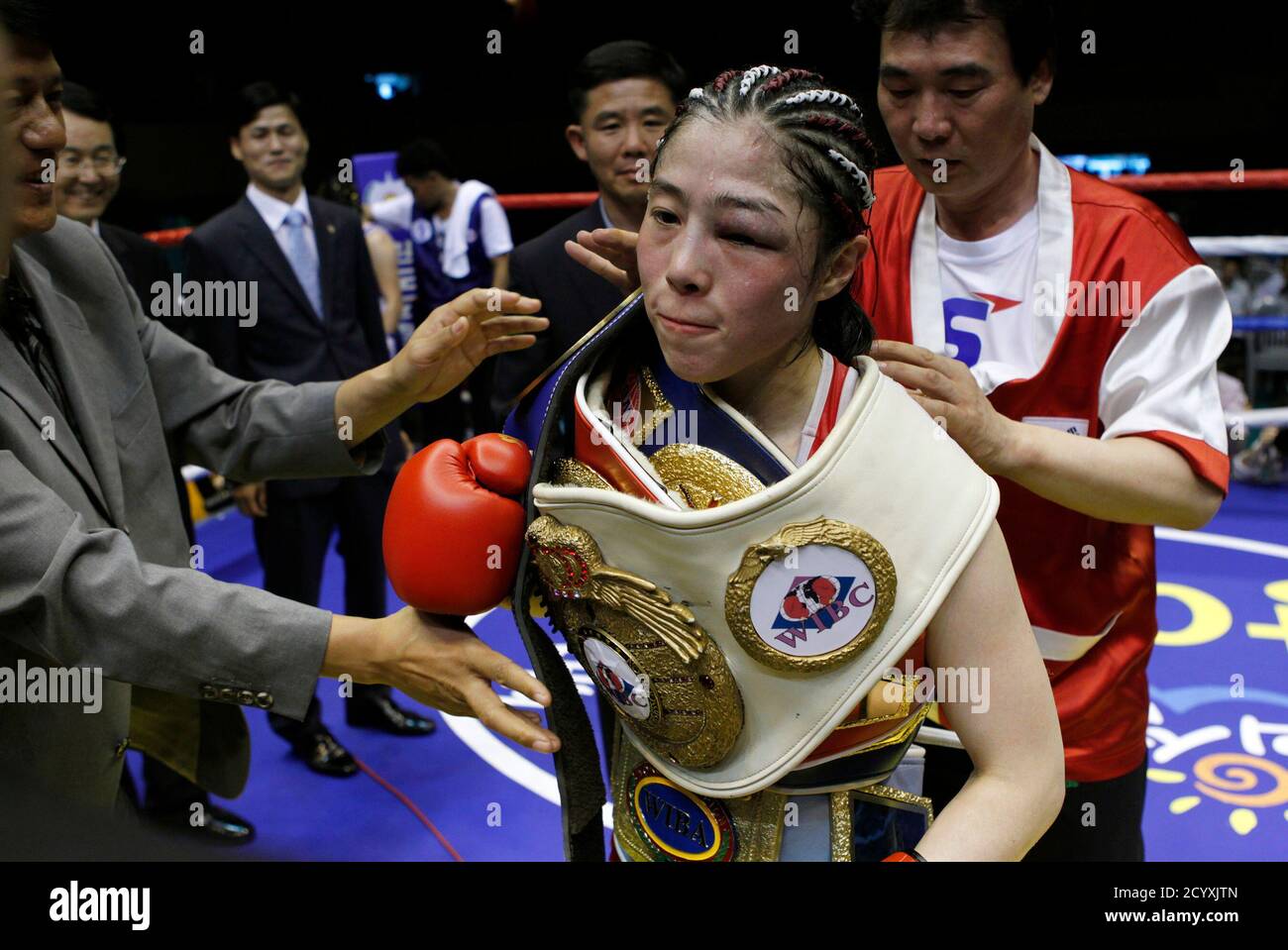 Kim Ju-hee, de Corée du Sud, est aidé par son Manager Jung Moon-ho (R) à  porter cinq ceintures de champion après sa victoire contre Fahpratan  Looksaikongdin, de Thaïlande, lors du combat de