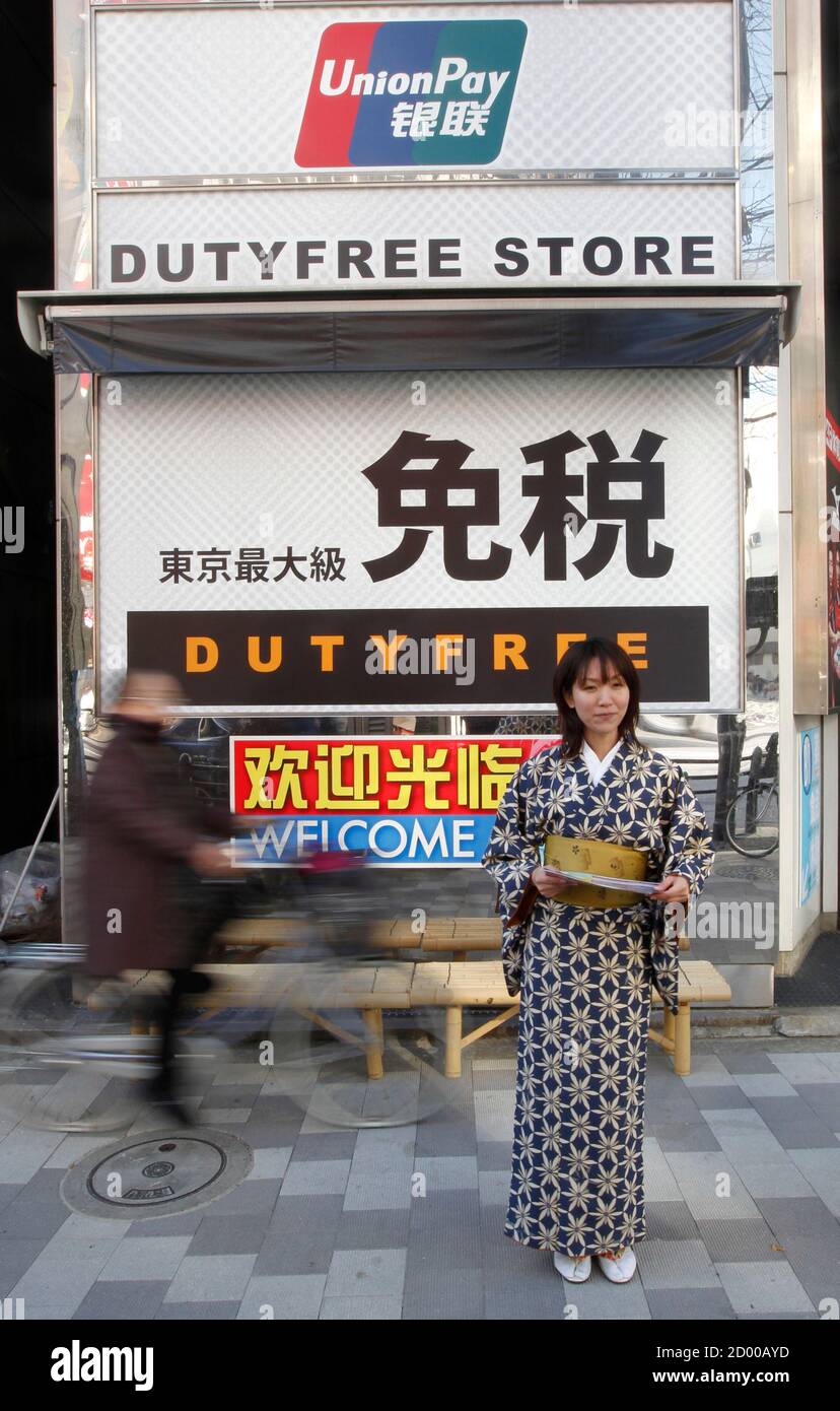 A Sales Clerk In Japan S Traditional Kimono Costume Stands In Front Of An Advertisement Board Featuring Chinese Bank Card Unionpay To Attract Chinese Shopper At The Electronic Shopping District Akihabara In Tokyo