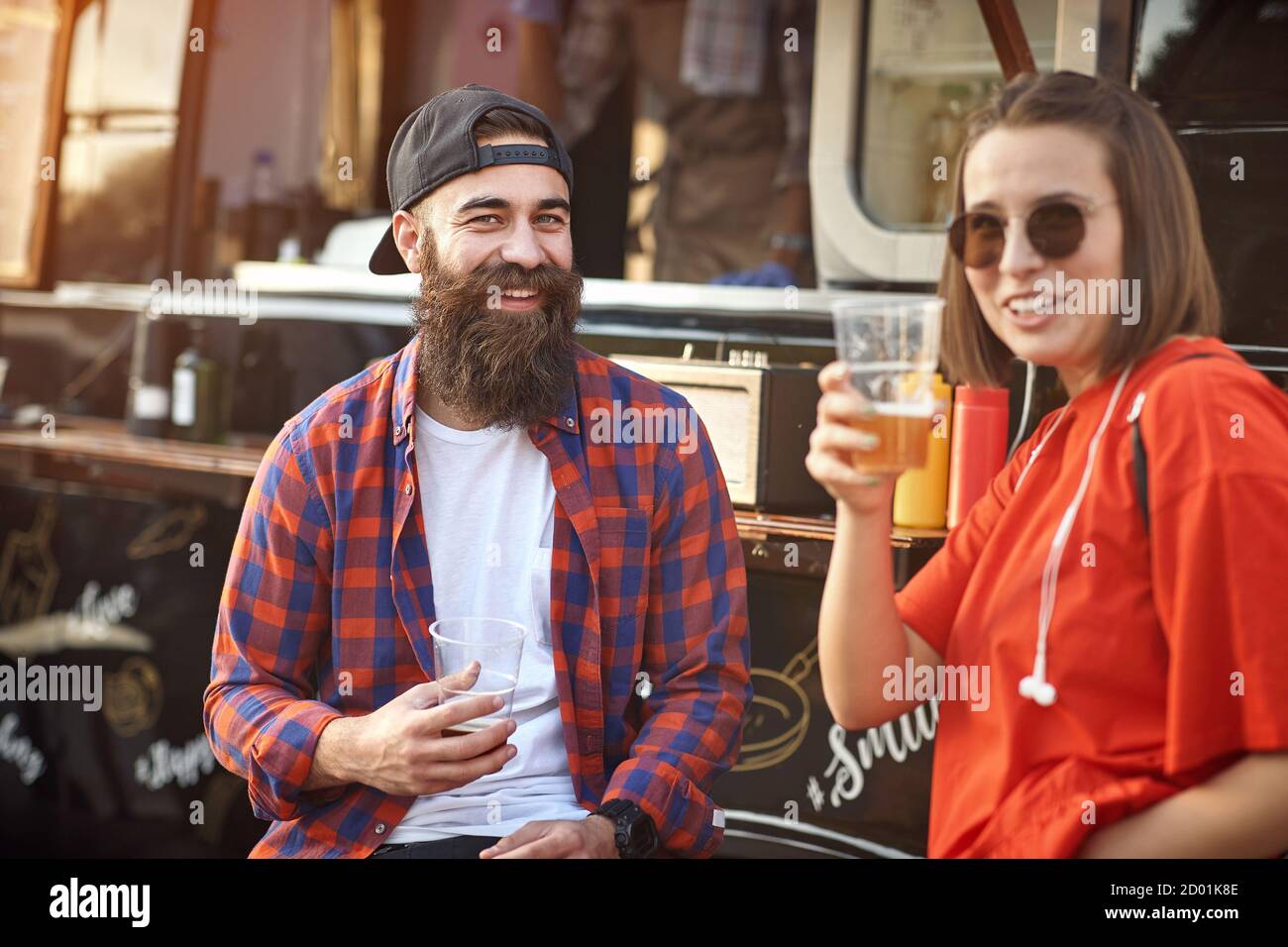 Un couple de Hipster se déchrée avec de la bière devant la nourriture chariot Banque D'Images