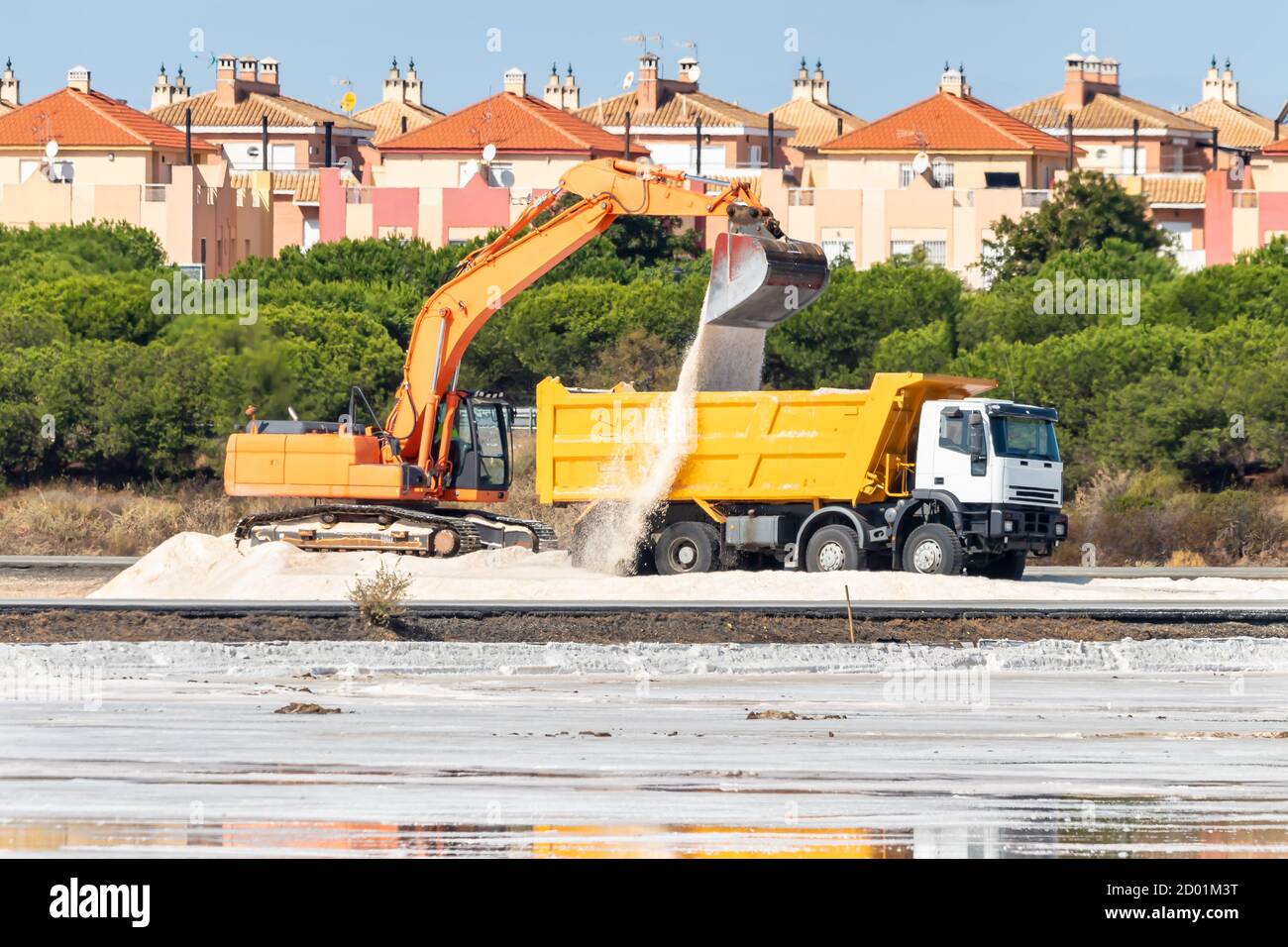 La pelle hydraulique charge du sel dans un camion. La production traditionnelle de sel de mer est le sel produit par l'évaporation de l'eau de mer. Banque D'Images