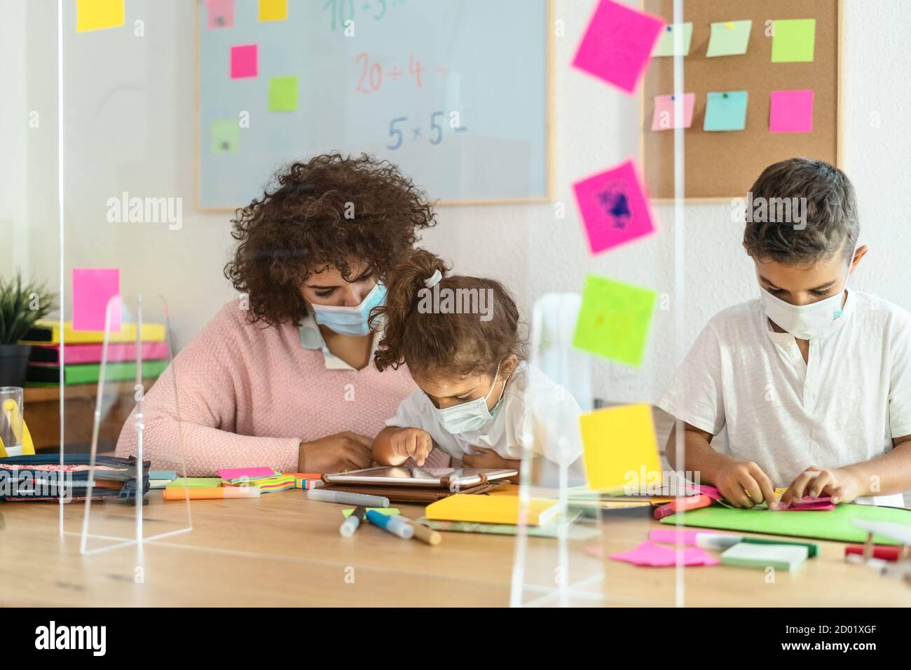 Enseignant avec des enfants portant un masque facial dans la salle de classe préscolaire pendant pandémie du virus corona Banque D'Images