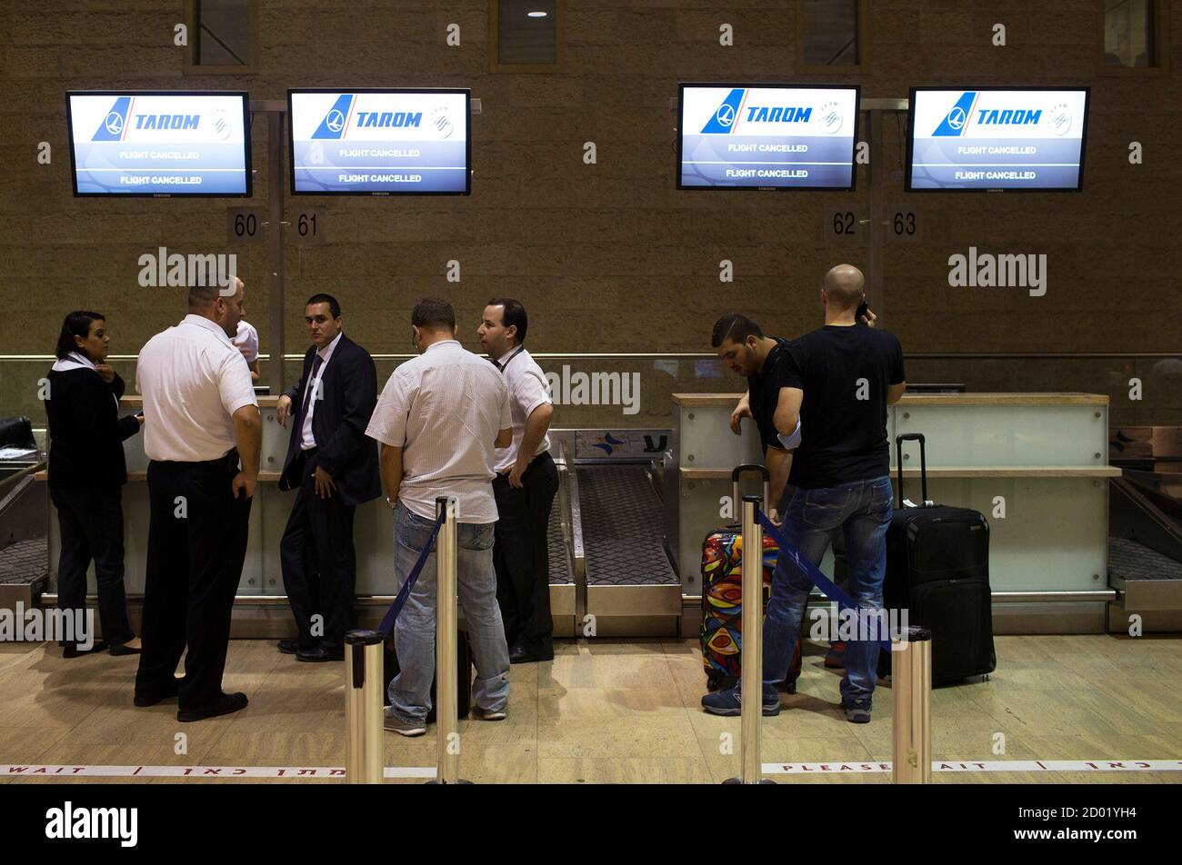 Passengers and airline staff stand near a check-in desk of an ...