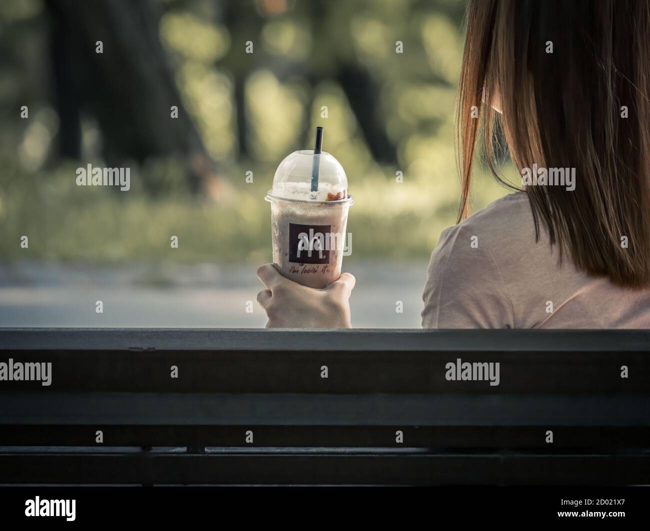 Bucarest/Roumanie - 09.19.2020: Fille sur un banc tenant un milkshake de McDonalds. Banque D'Images