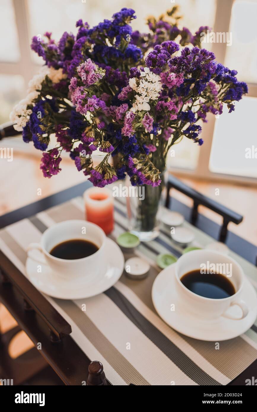 Deux tasses de café et bouquet de fleurs roses violettes dans un vase Banque D'Images