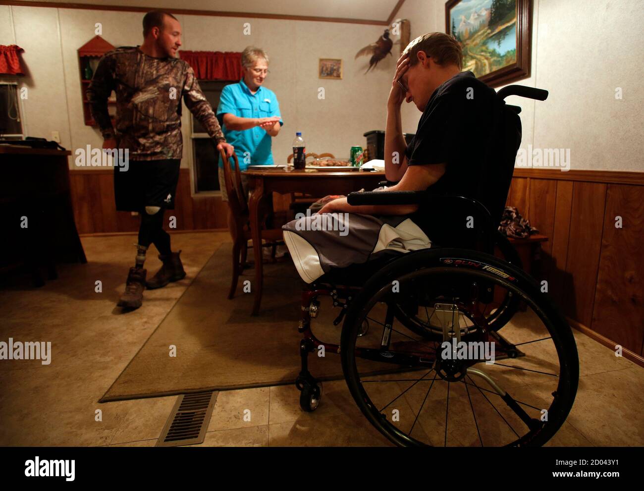 Sgt. Matt Krumwiede de l'armée américaine (R) est assis dans la douleur tandis que son ami Sgt. Jesse McCart et sa mère PAM Krumwiede parlent, après une journée de chasse dans un ranch à l'extérieur de San Antonio, Texas, dans cette photo du fichier du 2 novembre 2013. Krumwiede patrouillait en Afghanistan en 2012 lorsqu'il marche sur un engin explosif improvisé qui arracha les deux jambes, abîma le bras gauche et ouvrait sa cavité abdominale. Depuis, il a subi des dizaines de chirurgies et a passé du temps à se remettre au Brooke Medical Center de San Antonio, Texas, apprenant à marcher à nouveau avec l'utilisation de jambes prothétiques. En juin 201 Banque D'Images