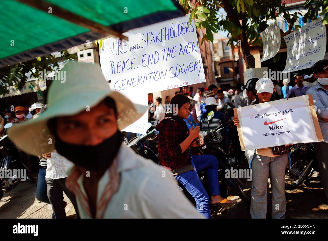 Garment workers hold signs during a gathering of workers from Sabrina ( Cambodia) Garment Manufacturing Corp, which produces clothing for U.S.  sportswear company Nike, at their union headquarters in Phnom Penh June 27,