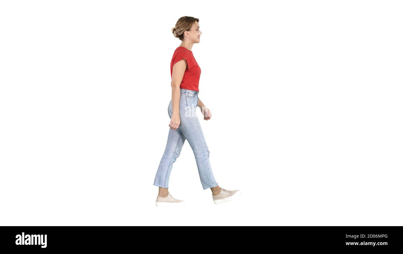 Femme en t-shirt rouge, jeans et baskets marchant sur le dos blanc Banque D'Images