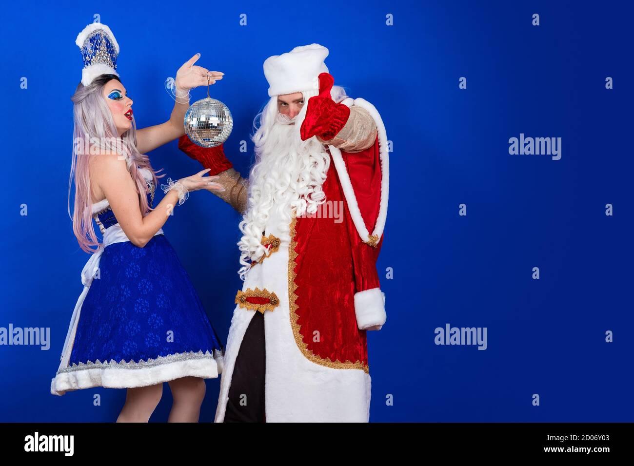 Père Noël émotionnel sous un manteau rouge et neige jeune fille dans un  costume bleu avec boule lumineuse posant sur un arrière-plan bleu Photo  Stock - Alamy