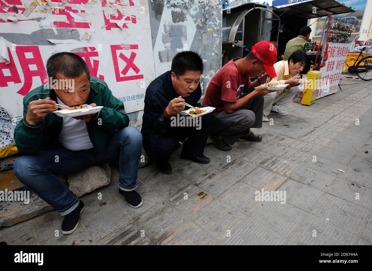 Men eat their lunch on a street after buying the food from a street vendor  in Beijing May 9, 2013. The price of one plate of meal with rice and  several side
