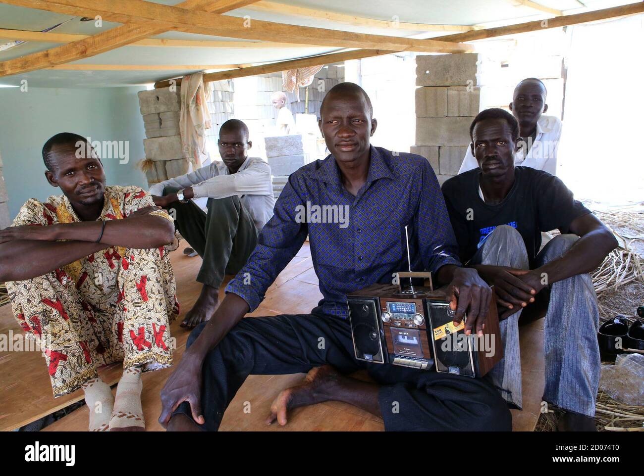 Men displaced by recent fighting in South Sudan listen to news on a radio  in a makeshift camp inside the United Nations Mission in Sudan (UNAMIS)  facility in Jabel, on the outskirts