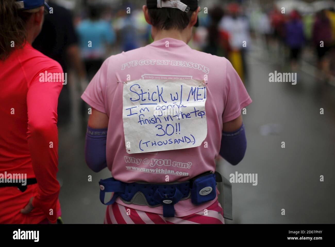 Phoebe Vanscoy-Giessler porte un panneau indiquant « Stick with Me! Je vais  finir dans le Top 30 (Thousand)' après avoir traversé la ligne d'arrivée du  119e Marathon de Boston à Boston, Massachusetts,