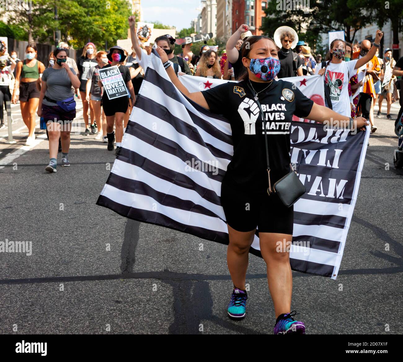 Une femme dans un t-shirt Black Lives Matter porte un drapeau BLM en route vers la marche sur Washington, 57 ans après MLK, Washington, DC, Etats-Unis Banque D'Images