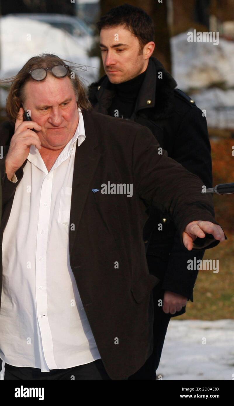 French actor Gerard Depardieu and mayor of Cetinje, Aleksandar Bogdanovic  (R) walk towards a waiting helicopter after a visit to Cetinje January 8,  2013. Depardieu failed to show up in court to