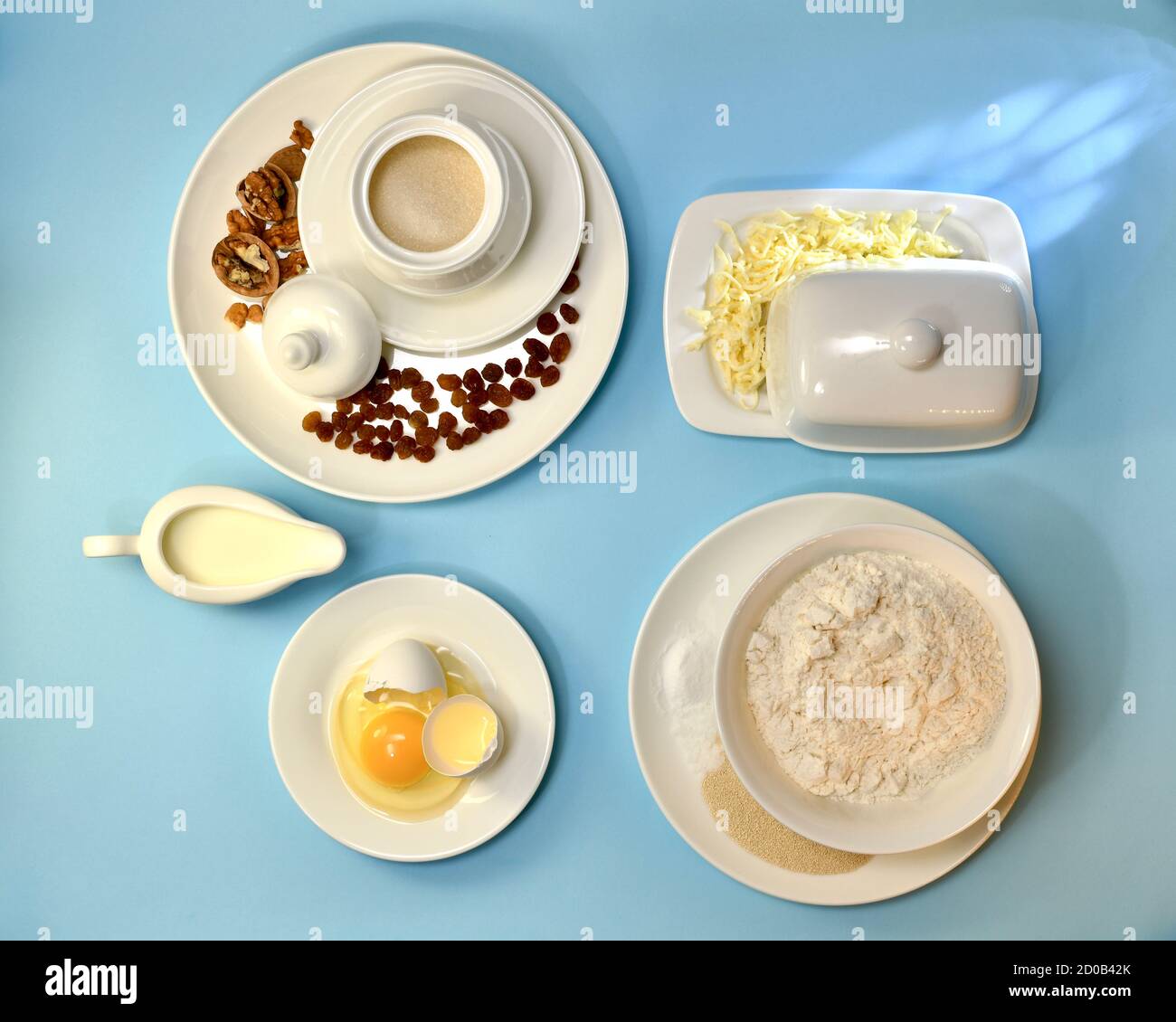 Ingrédients pour la pâte fermentée à base de levure. Dans les ustensiles en porcelaine blanche, la disposition sur fond bleu. Banque D'Images