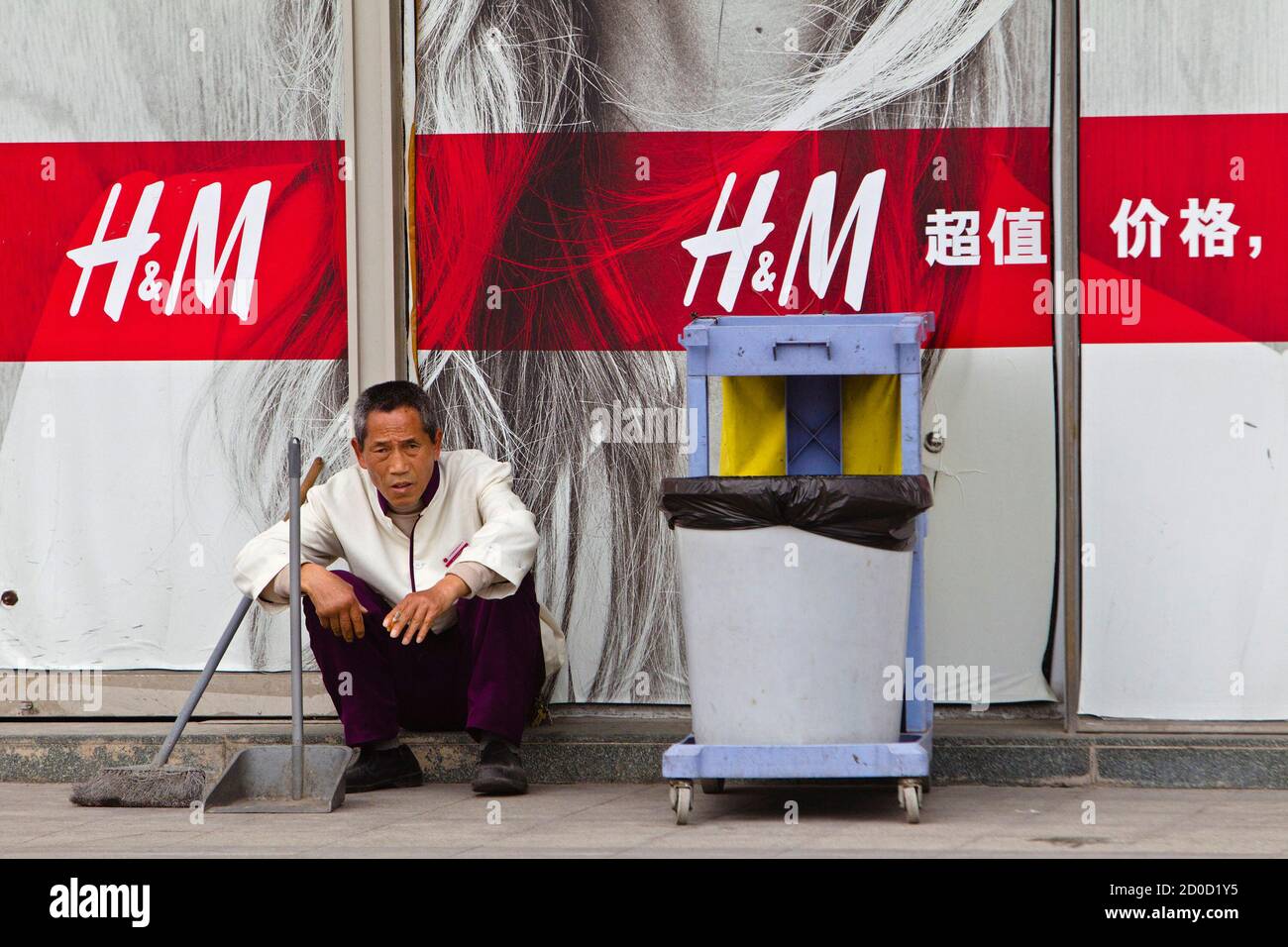 Un nettoyant se trouve devant un magasin H&M à Guangzhou, province de  Guangdong, le 26 février 2014. Les plus grandes marques de luxe au monde  ralentissent leur expansion en Chine, tandis que
