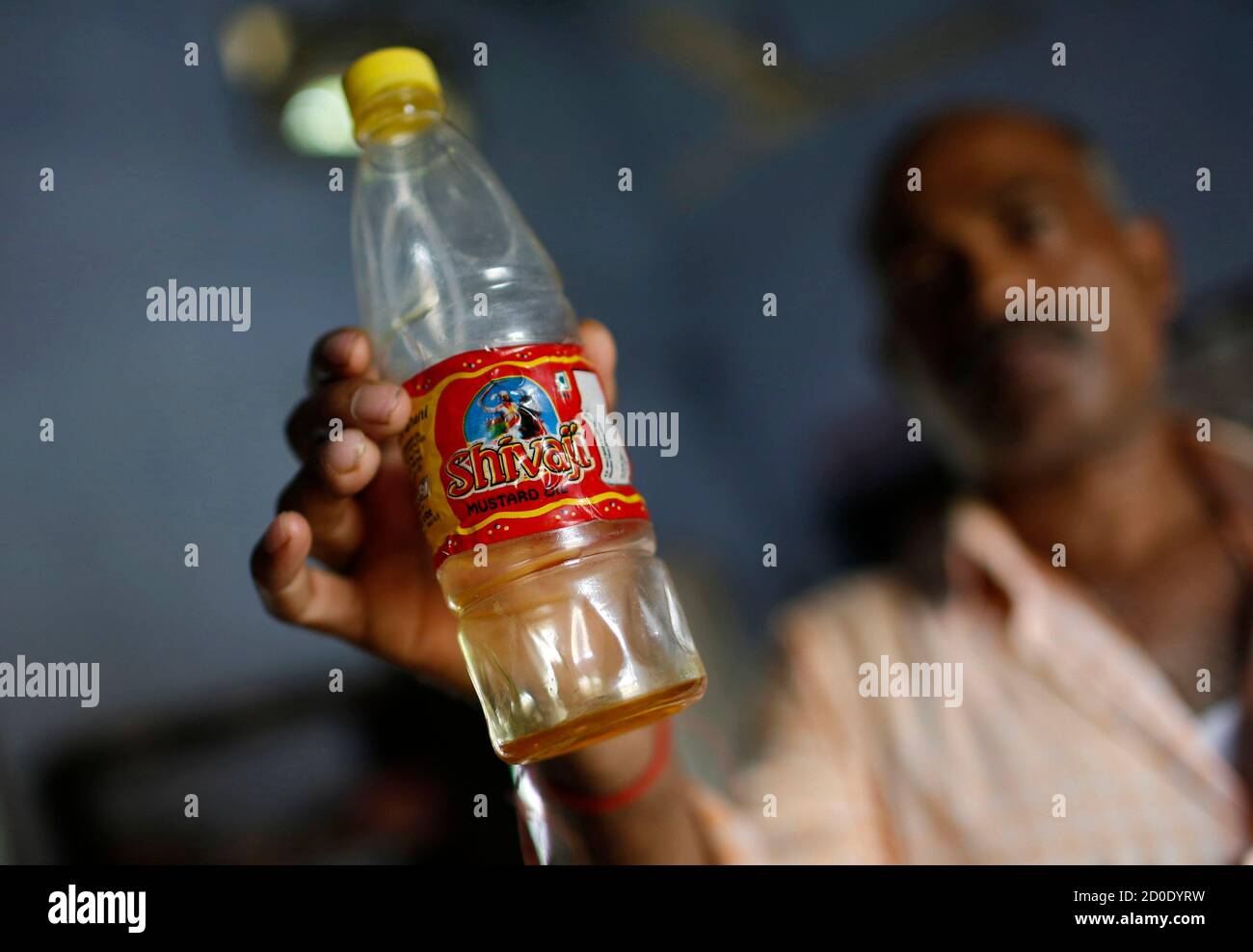 A Policeman In Civilian Clothes Shows A Bottle Containing Oil Which They Recovered From The School Where Contaminated Meals Were Served To Children On Tuesday At A Police Station In Masrakh At