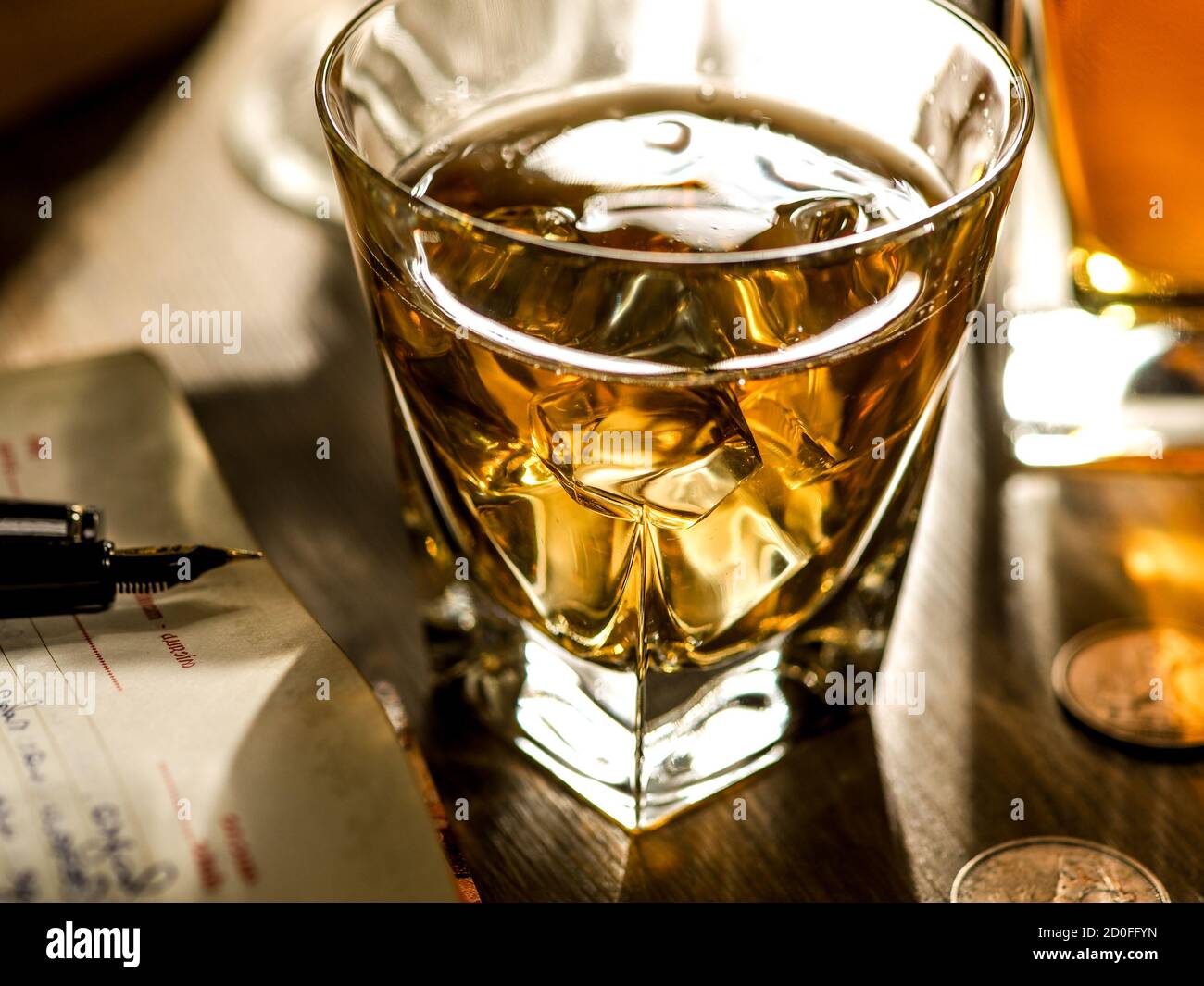 Verre de whisky, livres et journal tard dans la nuit Banque D'Images