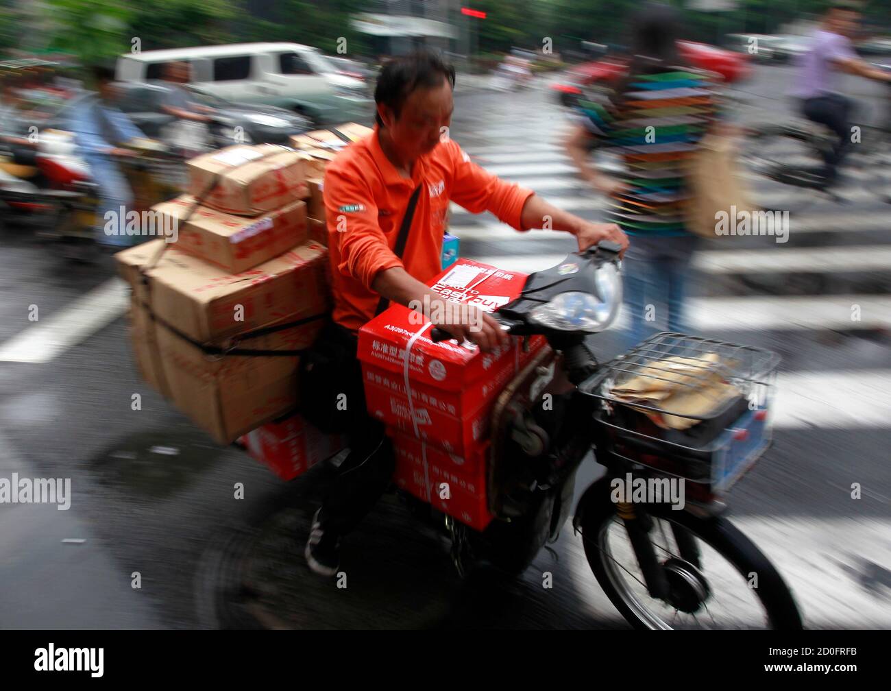 A man rides a motorcycle as he delivers a box in Shanghai July 11, 2012.  China's 35,000 express delivery companies can ship packages hundreds of  miles for less than the cost of