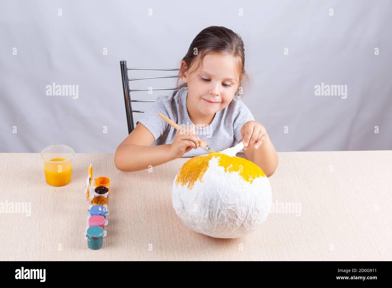 Un enfant avec plaisir et un sourire décore une citrouille maison pour Halloween, se préparant pour les vacances en isolement Banque D'Images
