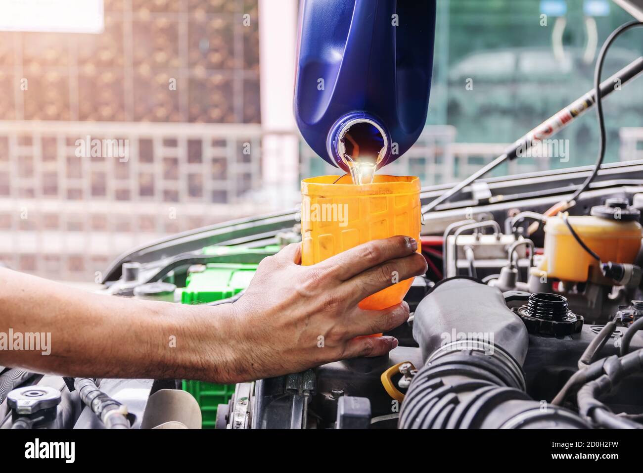 Auto mécanicien est le remplissage de l'huile moteur de la voiture à l'intérieur du centre de réparation automobile, l'industrie automobile et les idées de garage. Banque D'Images