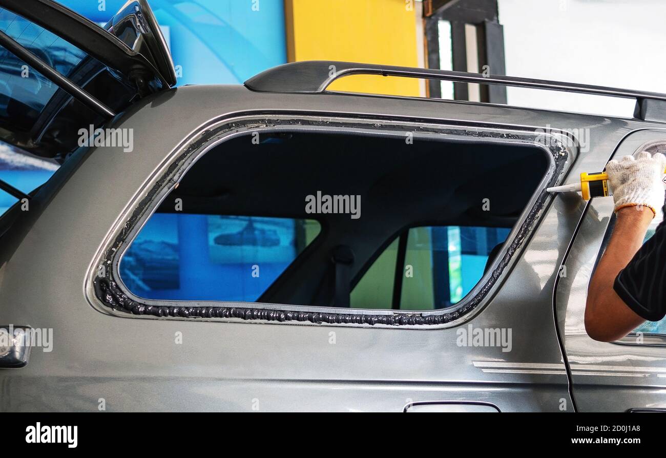 Les techniciens utilisent du silicone pour installer la vitre arrière droite de la voiture. Banque D'Images Les techniciens utilisent du silicone pour installer la vitre arrière droite de la voiture. Banque D'Images