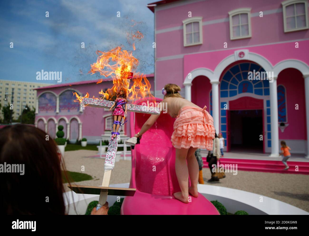 Les activistes du groupe de défense des droits des femmes Femen brûlent une  poupée de barbie sur une croix alors qu'ils protestent à l'extérieur d'une  « maison de rêve Barbie » de