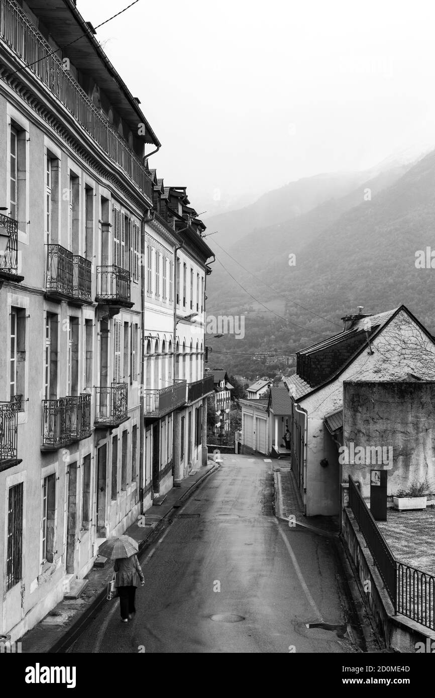 Vieille dame qui marche dans une vieille ville française dans les Pyrénées un vendredi matin brumeux. Banque D'Images