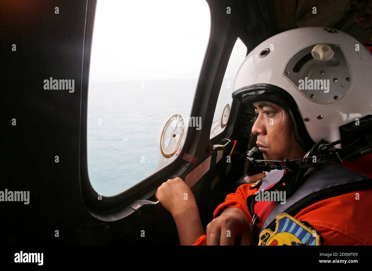 A crew member of an Indonesian Air Force NAS 332 Super Puma helicopter  looks out a window during a flight with Muslim clerics to offer prayers for  the victims of AirAsia flight
