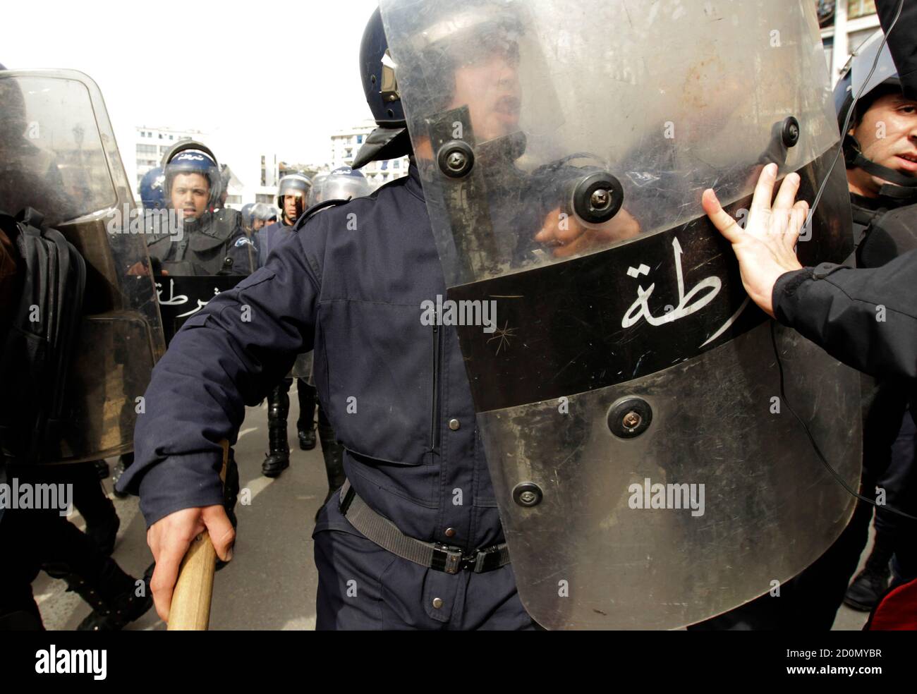 An anti-government protester pushes back riot policement during a demonstration in Algiers February 19, 2011. Algerian police in riot gear on Saturday surrounded about 500 protesters trying to stage a march through the capital inspired by uprisings in other parts of the Arab world in defiance of a ban. REUTERS/Zohra Bensemra (ALGERIA - Tags: POLITICS CIVIL UNREST) Banque D'Images
