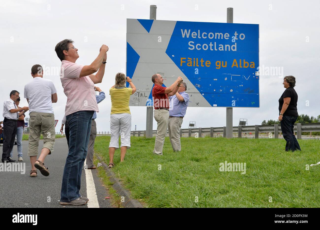 Swiss tourists take photographs next to a road that marks the England -  Scotland border, at a lay-by on the A1 road near Berwick August 20, 2013.  Signs of ancient conflict -