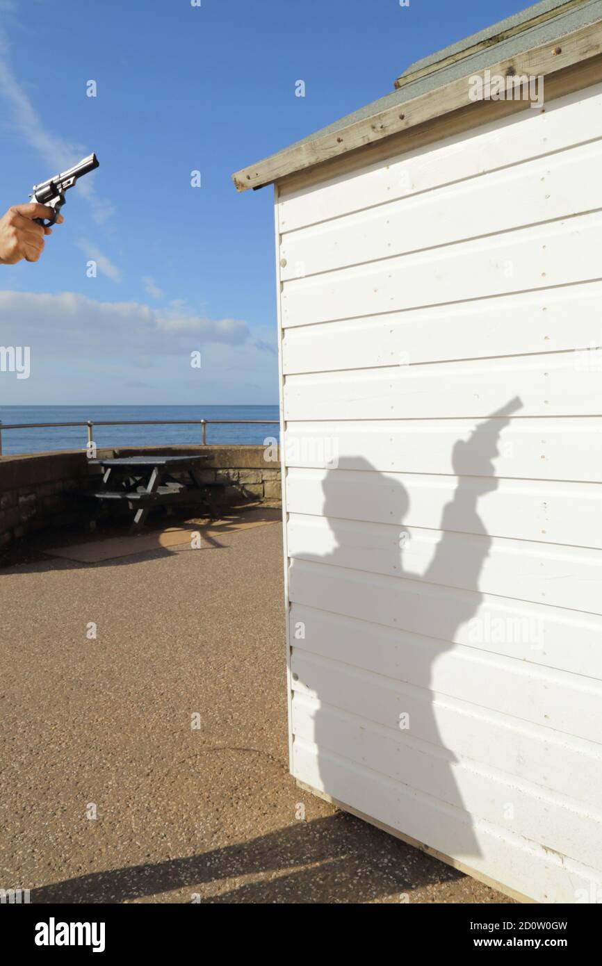 Silhouette d'un homme tenant un fusil près de la plage en bois blanc hutte Banque D'Images