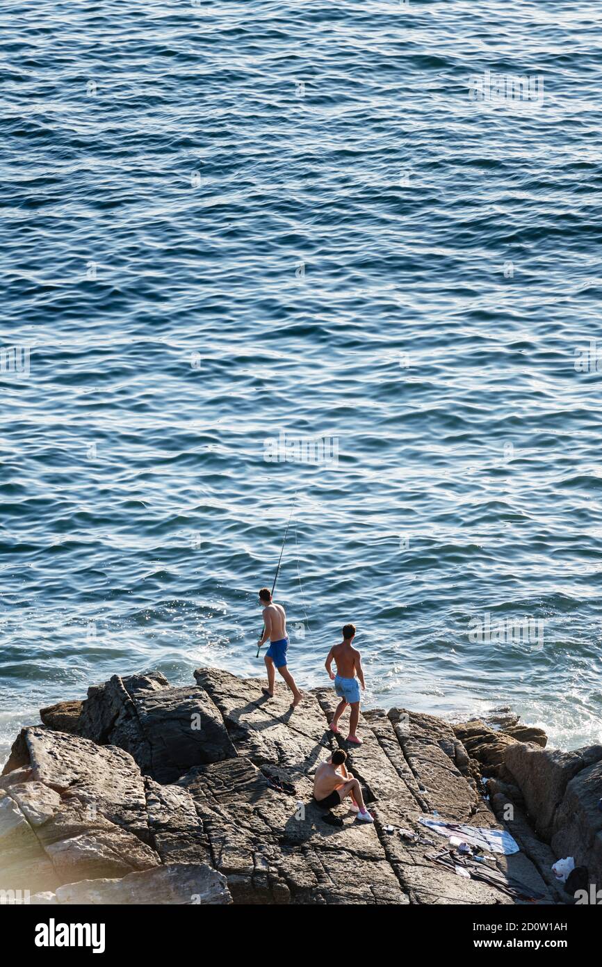 PORTONOVO, ESPAGNE - 14 AOÛT 2020 : trois jeunes pêcheurs pêchent par la mer lors d'une soirée calme et claire dans les Rias Baixas en Galice, Espagne. Banque D'Images