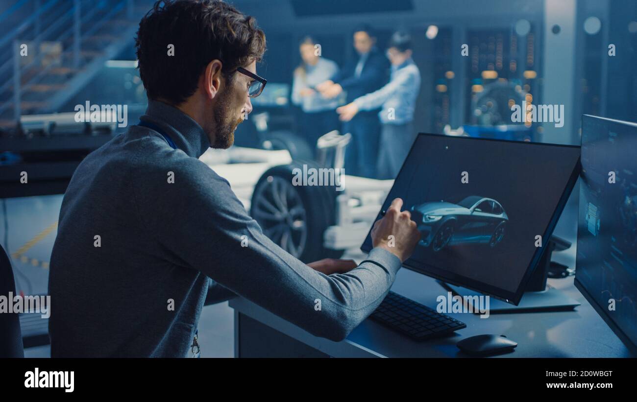 Professional Automotive Graphic Designer travaille sur le concept car Render Avec un stylet dans un laboratoire innovant de haute technologie Avec une voiture prototype Banque D'Images