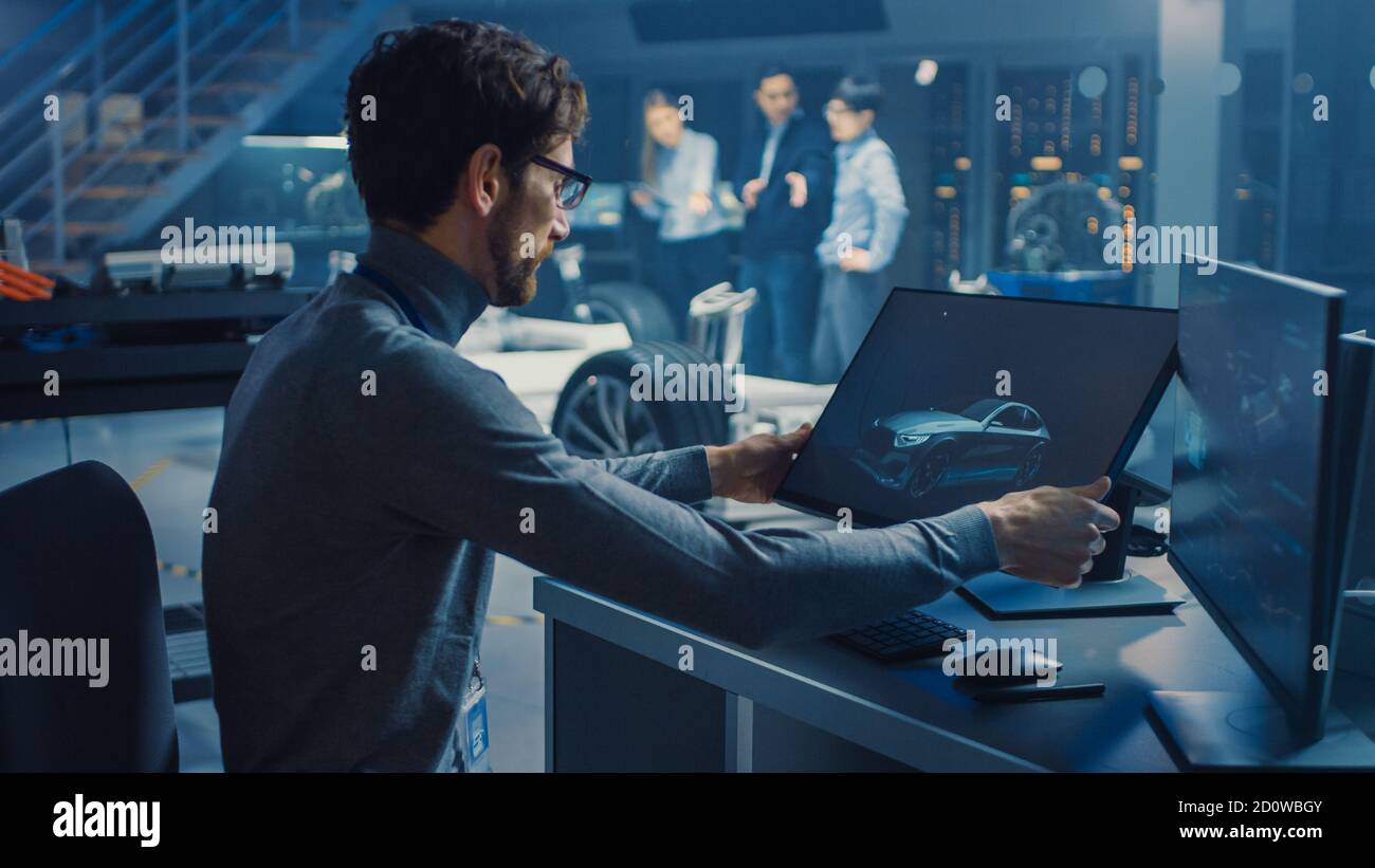 Professional Automotive Graphic Designer travaille sur le concept car Render Avec un stylet dans un laboratoire innovant de haute technologie Avec une voiture prototype Banque D'Images