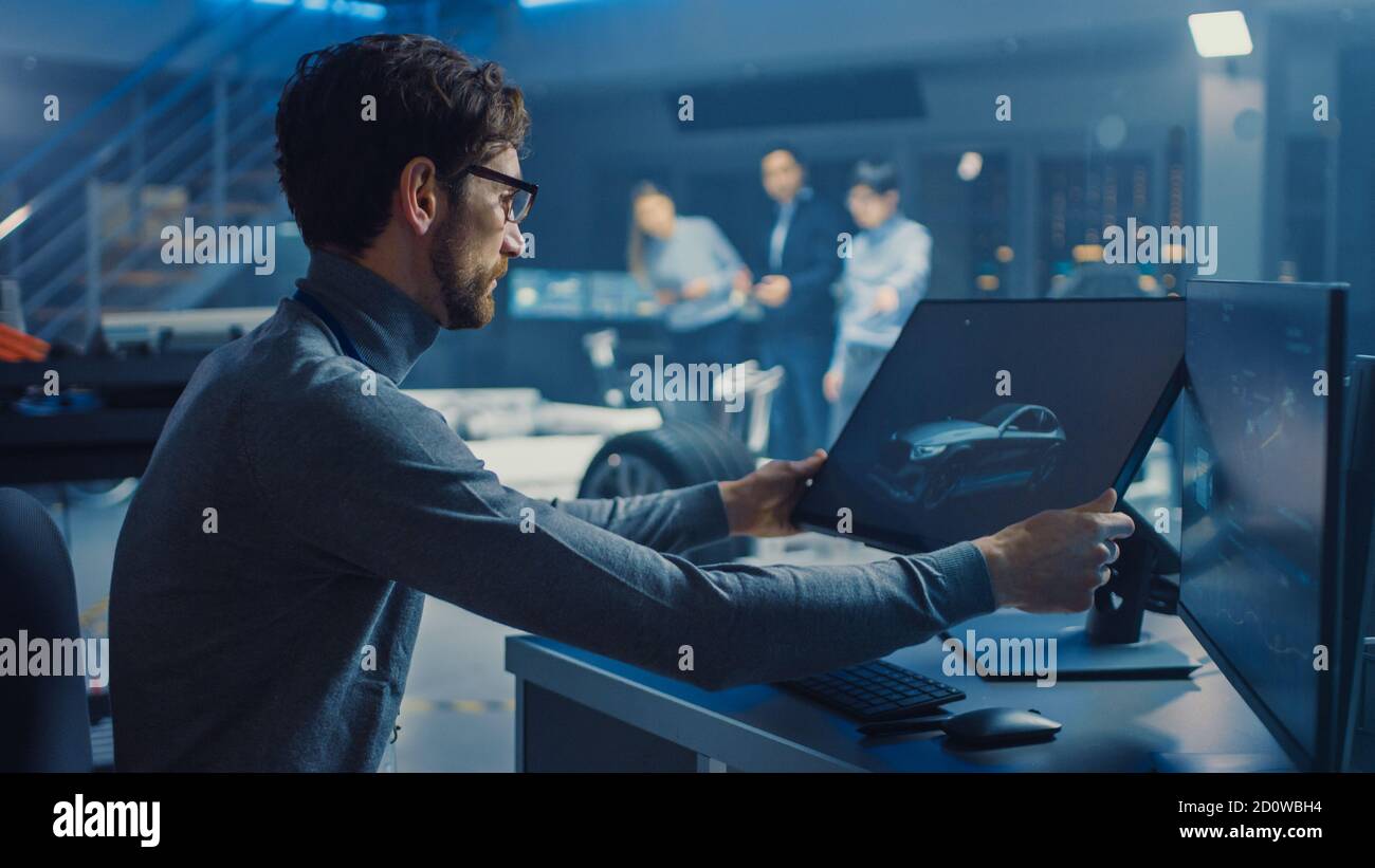 Professional Automotive Graphic Designer travaille sur le concept car Render Avec un stylet dans un laboratoire innovant de haute technologie Avec une voiture prototype Banque D'Images