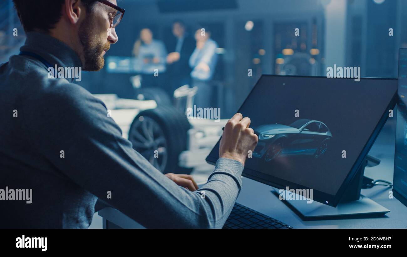Professional Automotive Graphic Designer travaille sur le concept car Render Avec un stylet dans un laboratoire innovant de haute technologie Avec une voiture prototype Banque D'Images