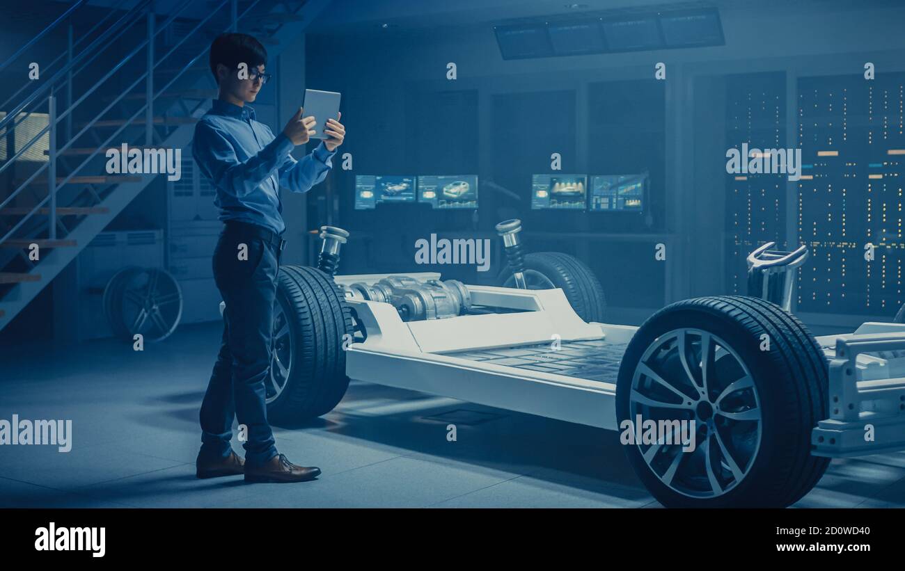 Ingénieur automobile travaillant sur la plate-forme de châssis de voiture électrique, utilisant la réalité augmentée d'ordinateur de tablette avec la modélisation de logiciel de CAO 3D. Innovant Banque D'Images