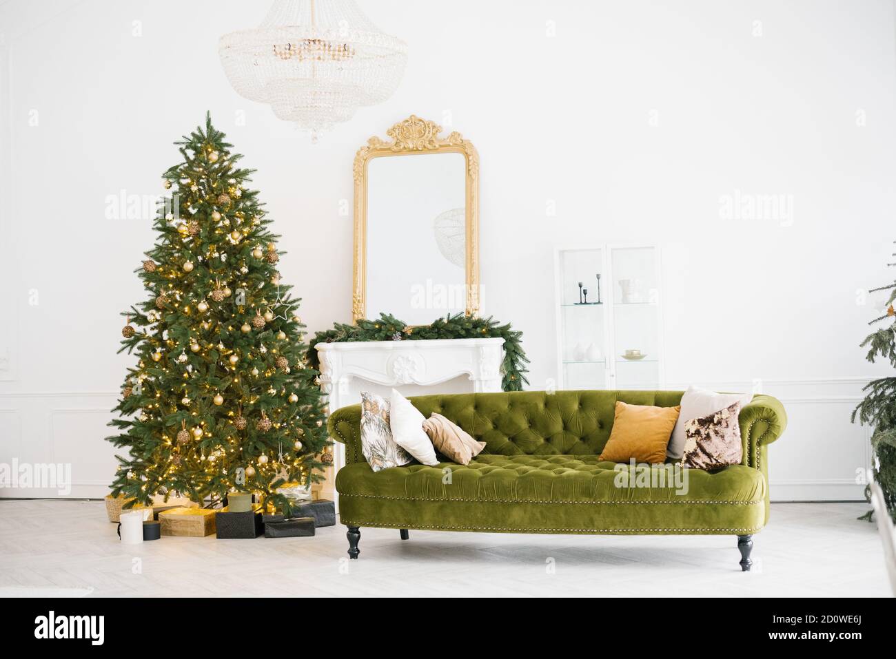 Design élégant de la salle de séjour avec décoration de Noël dans un style vintage avec un canapé vert, cheminée, sapin de Noël décoré avec des jouets et des lumières Banque D'Images