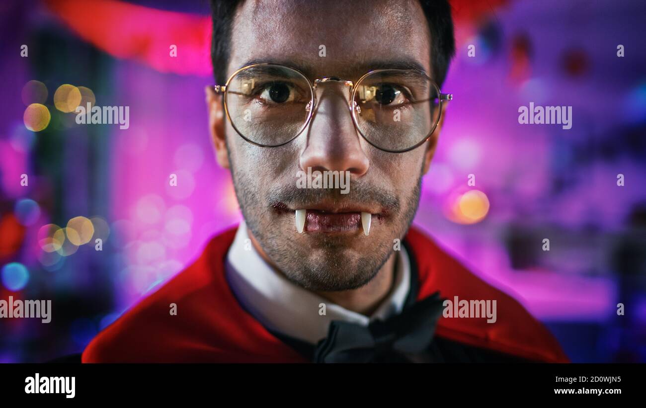 Halloween Costume Party: Gros plan Portrait du Comte Dracula sourire Creepily, montre ses sanglants sanglants Fangs mortels. En arrière-plan décoré par thème Banque D'Images