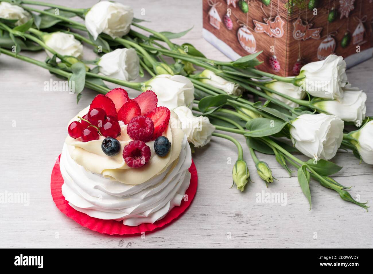 Gâteau à la meringue Pavlova avec crème et framboises, bleuets, fraises, raisins de Corinthe. Boîte cadeau pour le nouvel an Banque D'Images