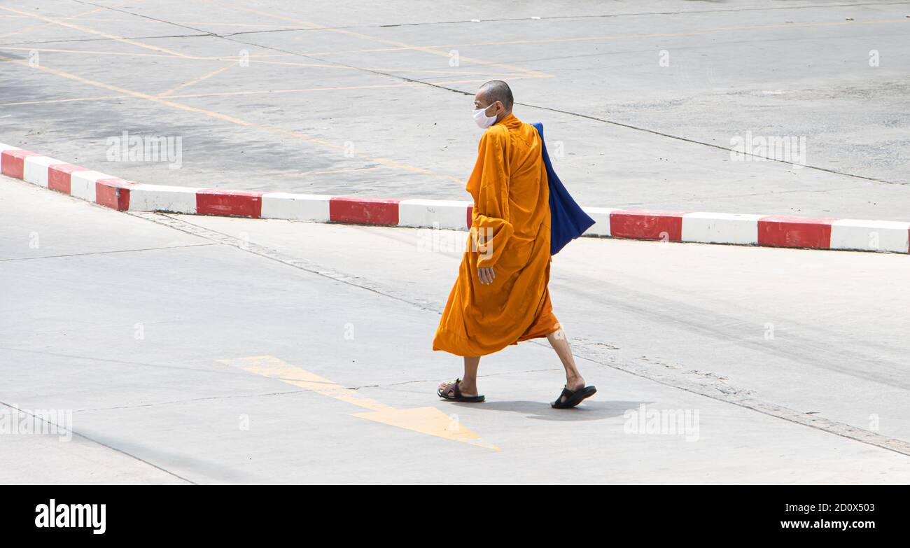 SAMUT PRAKAN, THAÏLANDE, JUL 03 2020, UN moine bouddhiste dans un costume  traditionnel orange descend une rue vide Photo Stock - Alamy