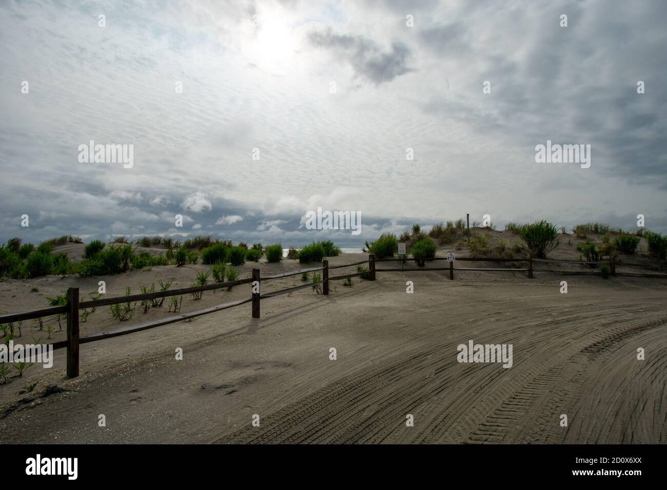 Un ciel orageux derrière une clôture en bois et un sable Dunes sur la plage Banque D'Images