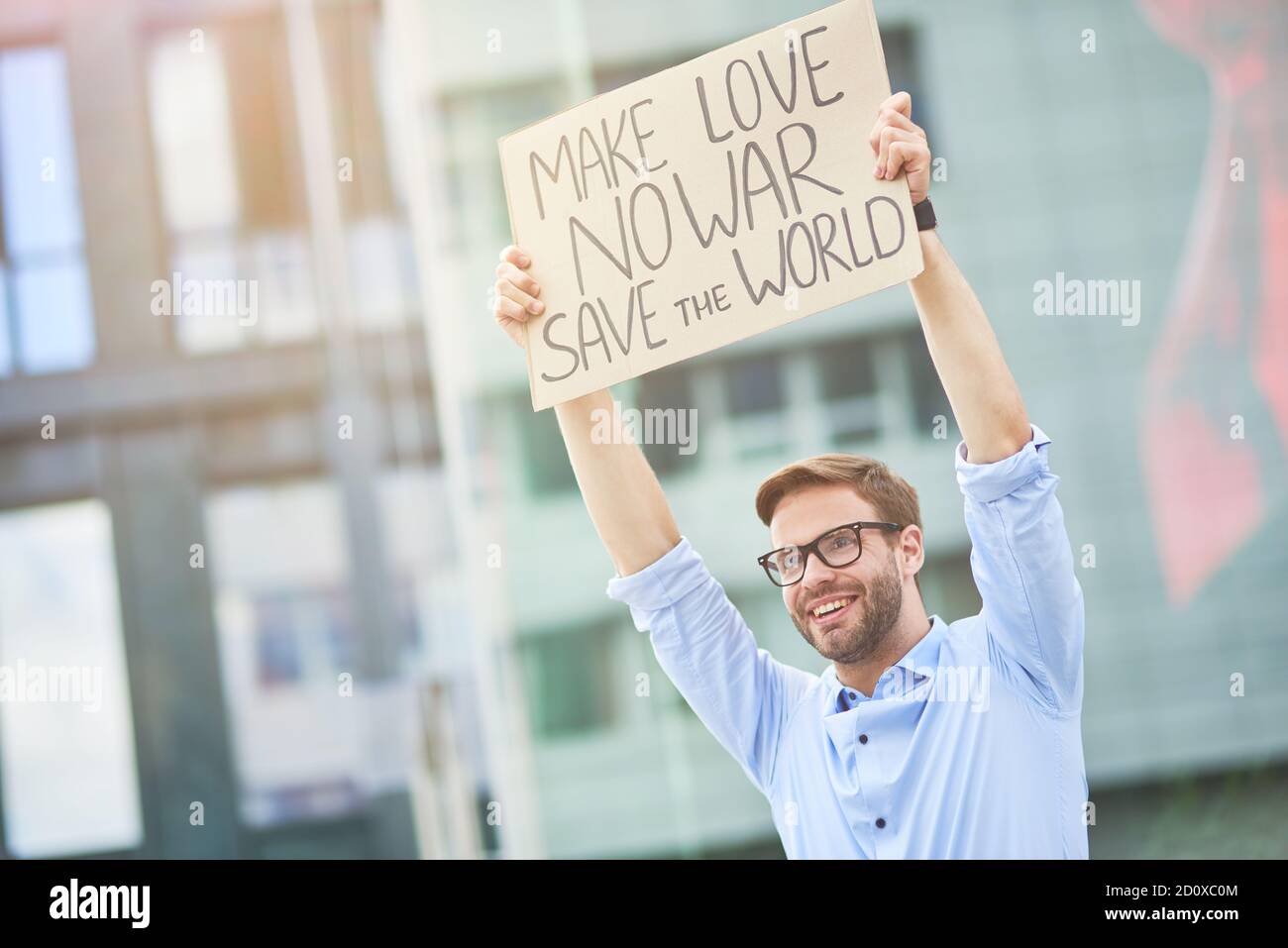 Sauver le monde. Un jeune activiste heureux tenant une bannière ou une affiche au-dessus de la tête tout en protestant contre la guerre, debout sur la route Banque D'Images