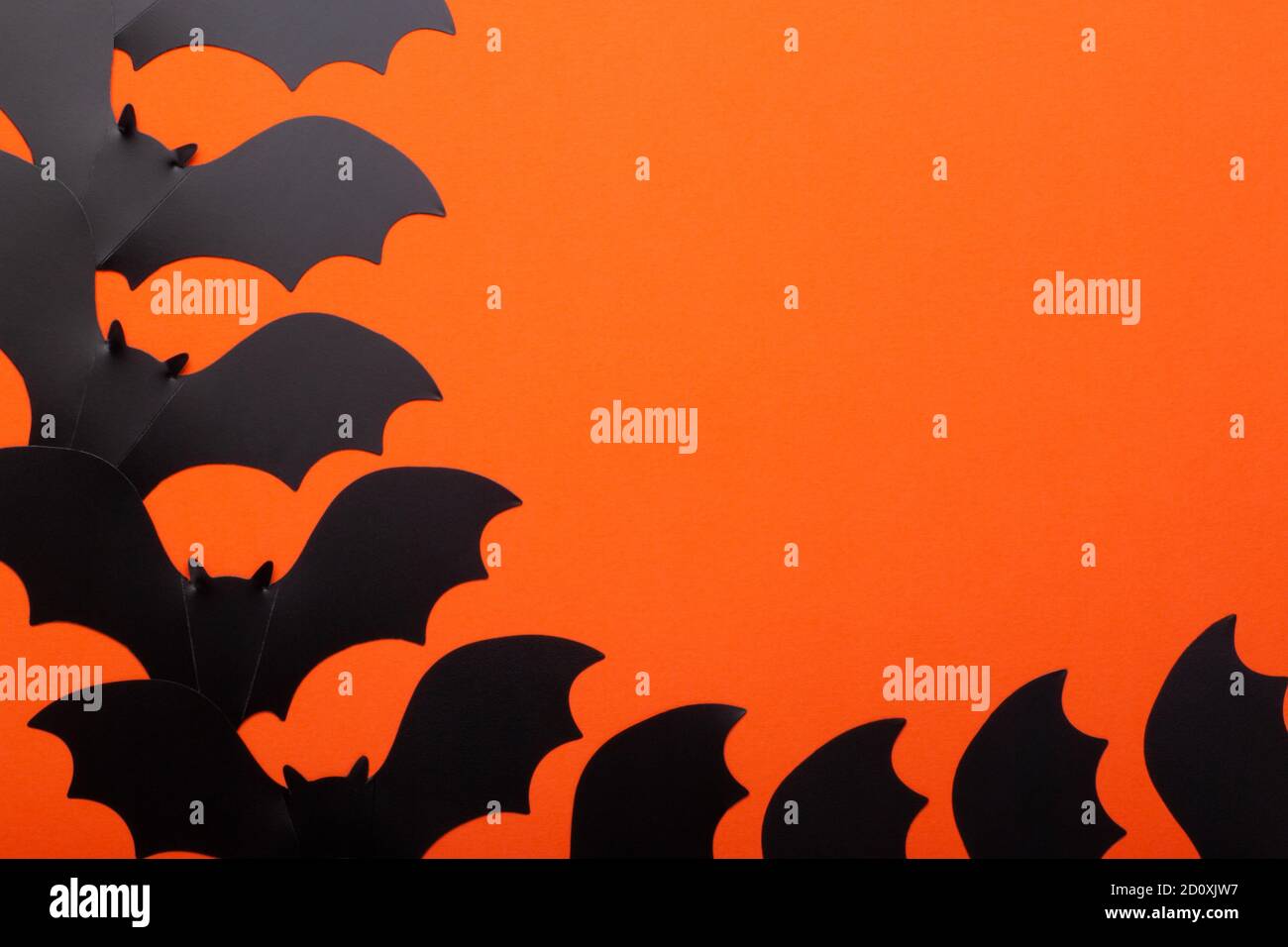 Plan conceptuel d'halloween sur fond orange vif. Batte en papier à la main noire comme symbole des fêtes d'halloween. Banque D'Images