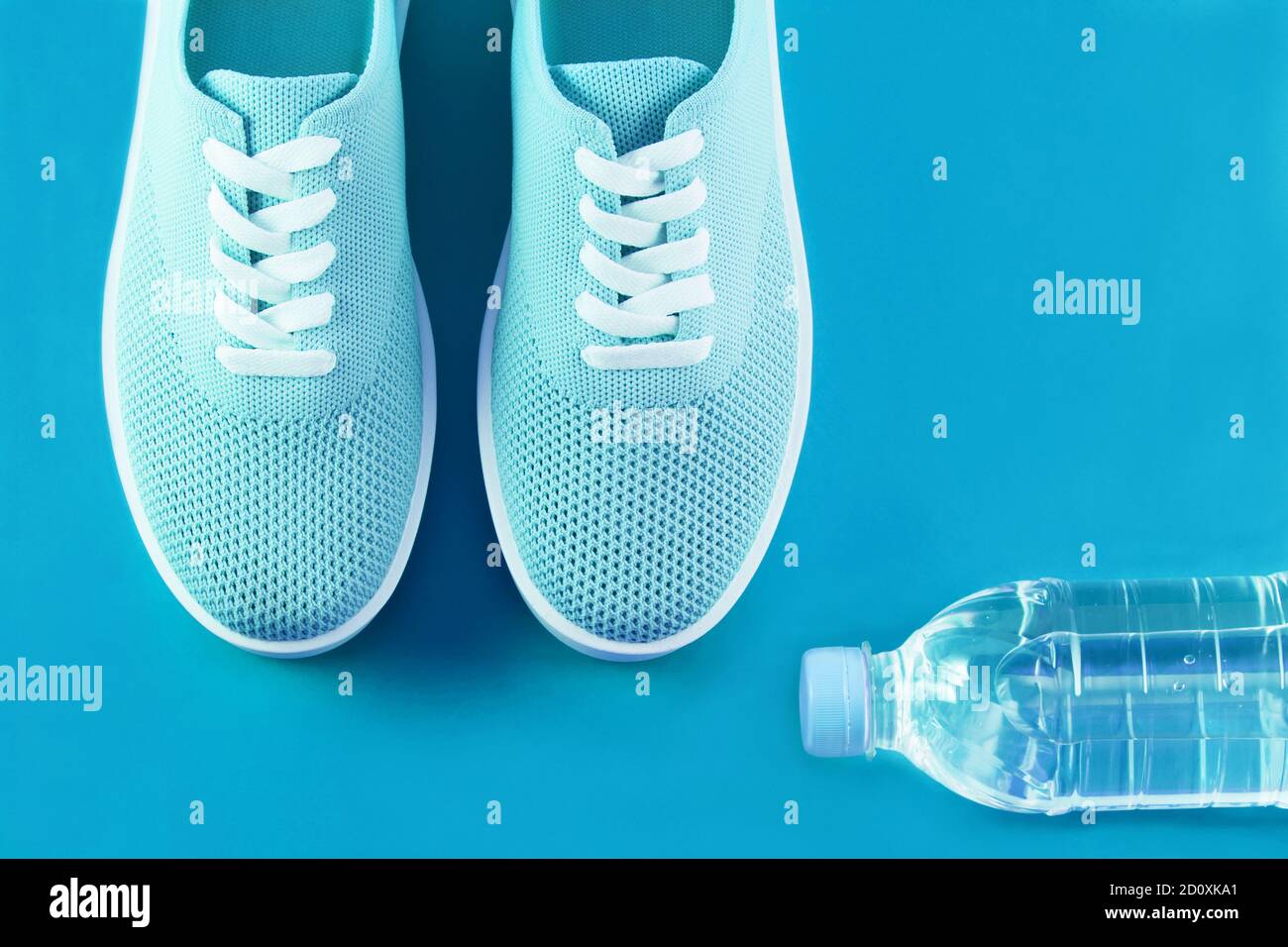 Menthe léger chaussures de sport et une bouteille d'eau mise en page sur un fond de couleur turquoise lumineux avec une place pour une inscription. Banque D'Images