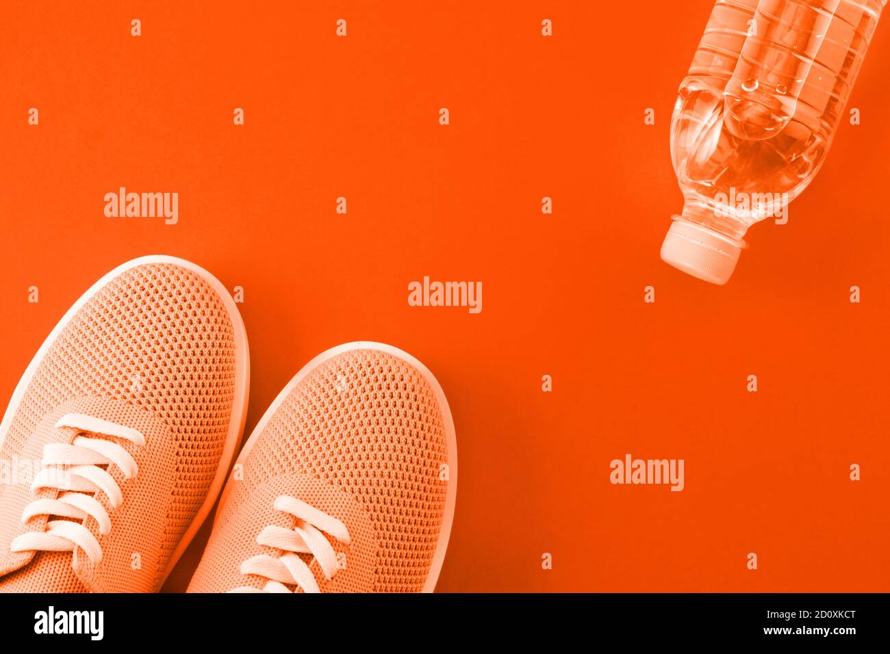 Chaussures orange et une bouteille d'eau sur un fond orange avec une place pour une inscription. Banque D'Images